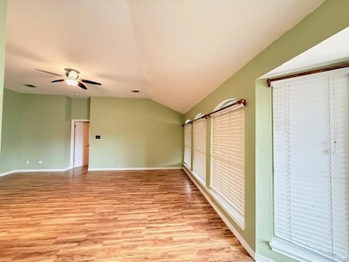 Unfurnished bedroom featuring light wood finished floors, vaulted ceiling, and a ceiling fan
