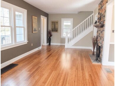 Spacious living room has wood flooring and a stone