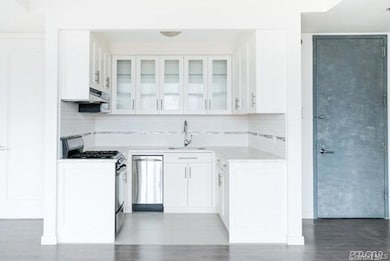 Kitchen with glass insert cabinets, white cabinetry, appliances with stainless steel finishes, and decorative backsplash