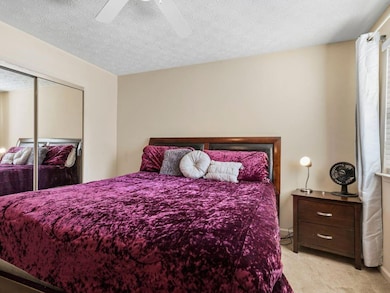 Bedroom with light carpet, a textured ceiling, ceiling fan, and a closet