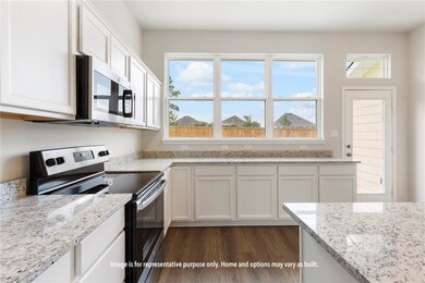 Kitchen featuring appliances with stainless steel finishes, light stone counters, white cabinets, and plenty of natural light