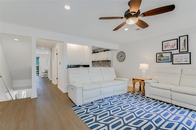 Living room featuring a ceiling fan, light wood f