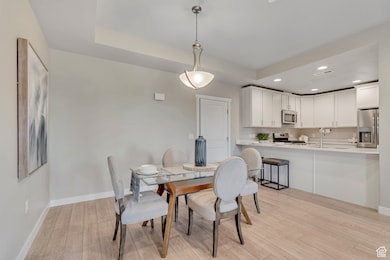 Dining space featuring recessed lighting, light wood-style flooring, and a raised ceiling
