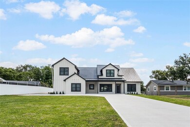 This home stands elegantly amidst a lush green field and at the back is the beautiful Lake Ariana. The house features the long driveway leading up to it. Surrounding the house are tall trees, adding to the serene and picturesque setting