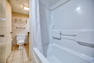Full bath featuring tile patterned floors, toilet, and shower / bath combo
