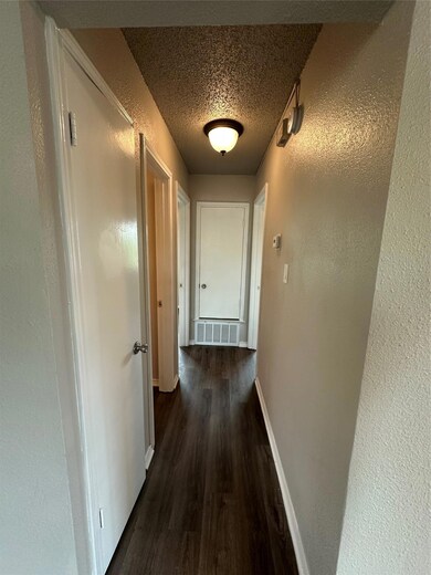 Hall with wood finished floors, baseboards, a tex