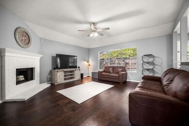 Living room with a fireplace, ceiling fan, and dar
