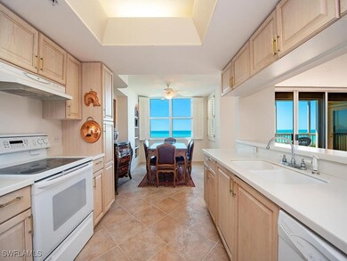 Kitchen with white appliances, light brown cabinets, a sink, and under cabinet range hood