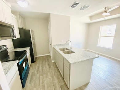 Kitchen featuring appliances with stainless steel finishes, a peninsula, light wood-style floors, light stone counters, and a ceiling fan