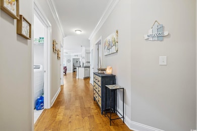Corridor featuring crown molding, light wood finished floors, and baseboards