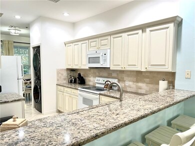Kitchen with light stone counters, white appliances, cream cabinets, tasteful backsplash, and recessed lighting