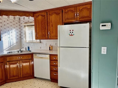 Kitchen with brown cabinets, white appliances, light floors, and light countertops