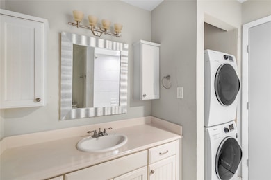 Bathroom with stacked washer and clothes dryer and vanity