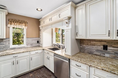 Kitchen featuring decorative backsplash, dishwasher, light stone counters, plenty of natural light, and recessed lighting