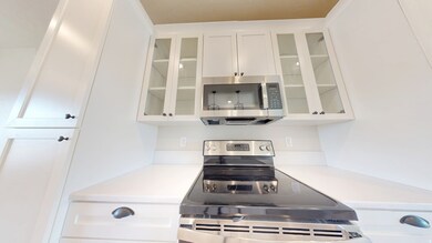 Kitchen featuring white cabinets, appliances with stainless steel finishes, and glass insert cabinets