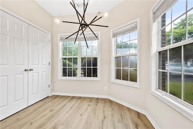 Unfurnished dining area with a chandelier, light wood finished floors, and baseboards