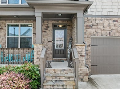 Entrance to property with a porch, stone siding, and driveway