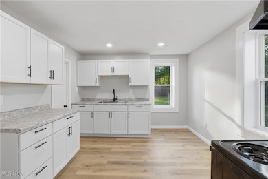 Kitchen with white cabinets, light wood-style floors, light countertops, recessed lighting, and ventilation hood