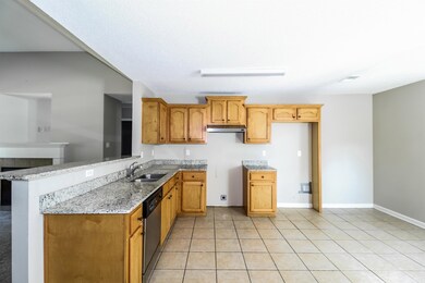 Kitchen featuring dishwasher, light stone counters, under cabinet range hood, light tile patterned floors, and a peninsula
