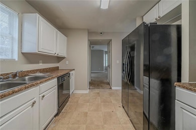 Kitchen featuring white cabinets, sink, and black 