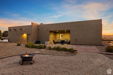 Back of house at dusk with a patio, stucco siding, and a fire pit