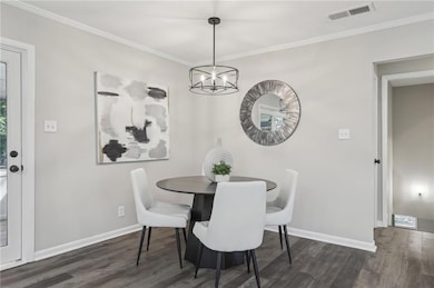 Dining area with wood finished floors, a chandelier, baseboards, and crown molding