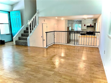 Unfurnished living room featuring light wood-style flooring, a sink, stairway, and a towering ceiling