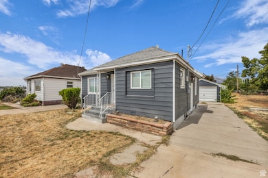 Bungalow-style house featuring a detached garage, an outdoor structure, and a shingled roof