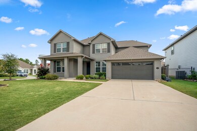 This stunning view highlights the immaculate curb appeal with lush, pristine landscaping surrounding the home. The exterior features modern brick and a spacious double-wide driveway that leads to the garage with epoxy flooring, added in 2021.