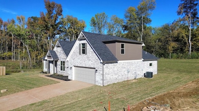 View of side of home with a yard, a garage, brick siding, and concrete driveway