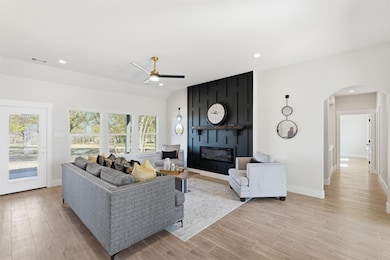 Living room with a fireplace, light wood-style flooring, recessed lighting, a ceiling fan, and arched walkways