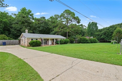 Single story home featuring covered porch, concrete driveway, a chimney, and brick siding