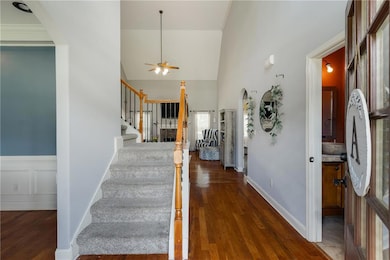 Foyer entrance featuring ceiling fan, wood finished floors, stairway, and high vaulted ceiling