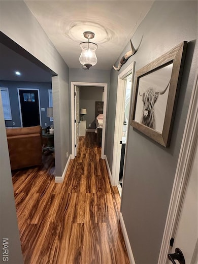 Corridor featuring dark wood-style floors and baseboards