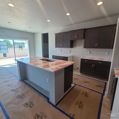 Kitchen with recessed lighting, dark brown cabinets, a textured ceiling, an island with sink, and light countertops
