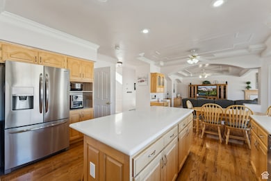 Kitchen featuring stainless steel refrigerator with ice dispenser, a ceiling fan, a center island, dark wood-style flooring, and recessed lighting