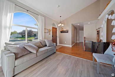 Living area with light wood finished floors, a chandelier, and high vaulted ceiling