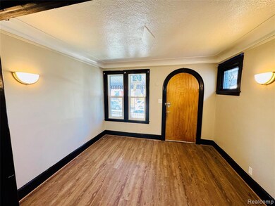 Unfurnished room with arched walkways, a textured ceiling, wood finished floors, and crown molding