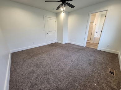 Unfurnished bedroom featuring dark colored carpet and ceiling fan