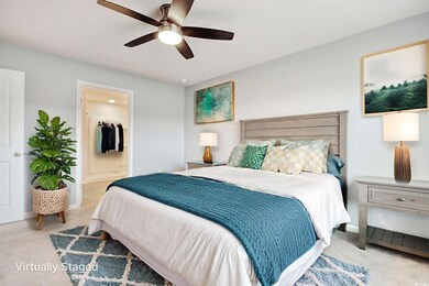 Bedroom featuring light carpet, a ceiling fan, and connected bathroom