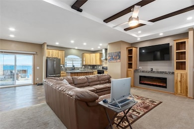 Open concept living room with abundant natural lighting, ceiling fan, electric fireplace entertainment center