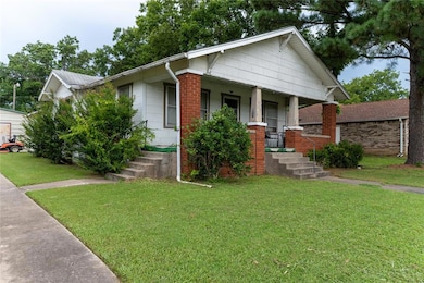 View of front of house featuring covered porch, a front yard, and brick siding