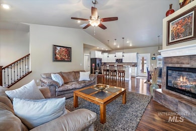 Living area with ceiling fan, vaulted ceiling, dark wood-type flooring, a fireplace, and recessed lighting