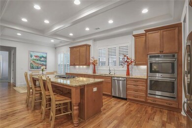 Kitchen with stainless steel appliances, brown cabinetry, light wood-style floors, a kitchen island, and recessed lighting