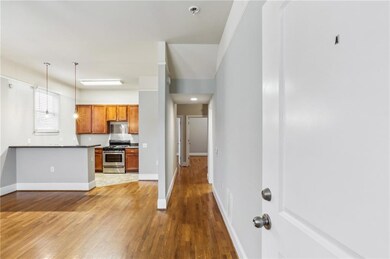 Kitchen featuring appliances with stainless steel finishes, wood finished floors, brown cabinets, decorative light fixtures, and dark countertops