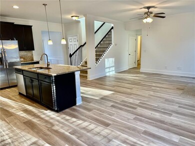 Kitchen featuring crown molding, backsplash, pendant lighting, light stone counters, and an island with sink