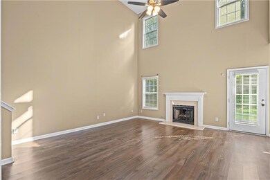 Unfurnished living room featuring a towering ceiling, a ceiling fan, a fireplace, and wood finished floors