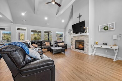 Living room features gas log fireplace, vaulted ceilings with accent beams, and flooring that is continued through kitchen and both bedrooms downstairs.