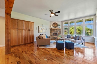 Living area with a fireplace, ceiling fan, and light wood-style floors