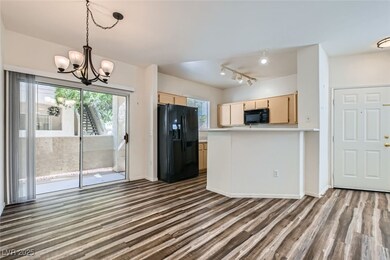 Kitchen with black appliances, decorative light fixtures, a peninsula, dark wood-type flooring, and light brown cabinets